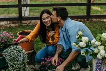 Naklejka premium Couple gardening together planting flowers and sharing a kiss