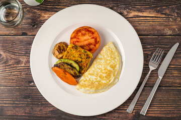 Rustic breakfast plate with fried eggs, grilled vegetables, and turkey bacon