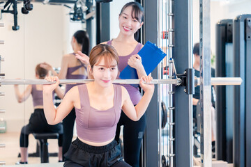 Fototapeta premium ジムで女性コーチのパーソナルトレーニングを受ける女性