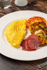 Rustic breakfast plate with fried eggs, grilled vegetables, and turkey bacon