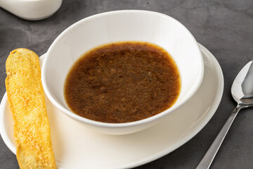 Steaming hot French onion soup served in a white bowl with golden toasted bread