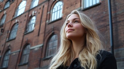 Fototapeta premium Young Woman with Flowing Blonde Hair Against Historical Building