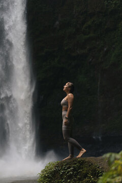 Woman practising yoga in front of waterfall on the island of Bali