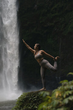 Woman practising yoga in front of waterfall on the island of Bali
