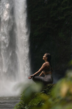Woman practising yoga in front of waterfall on the island of Bali