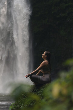 Woman practising yoga in front of waterfall on the island of Bali