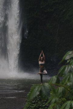 Woman practising yoga in front of waterfall on the island of Bali