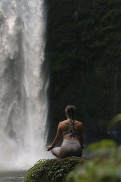 Woman practising yoga in front of waterfall on the island of Bali