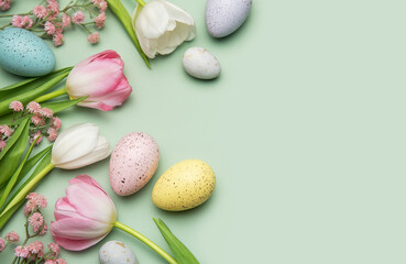 Easter eggs and tulips creating a border on pastel green background