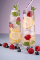 refreshing two tall glasses of lemon and berry infused water with mint sprigs, set against a soft lavender background, highlighting vibrant colors and cool hydration, pair, two, contrast, inviting