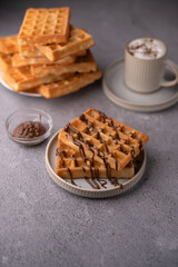 photo Delicious homemade waffles drizzled with rich chocolate sauce, served with a cup of frothy coffee, offering a perfect breakfast or dessert delight for food lovers everywhere
