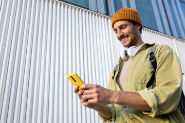 Smiling student using smartphone in front of modern building