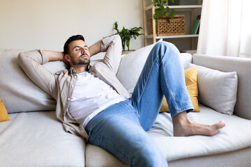 Caucasian man relaxing, sleeping on the couch with hands behind the head.