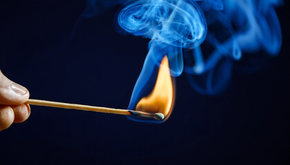 Burning match with bright flame and blue smoke on dark backdrop.