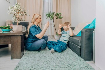 speech therapist engaging with young boy in nonverbal communication training, living room with warm...