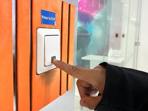 Initiating Access: A Human Finger Engages the "Press to Exit" Button to Activate an Automated Sliding Door, Highlighting the Interaction Between User and Modern Building Technology