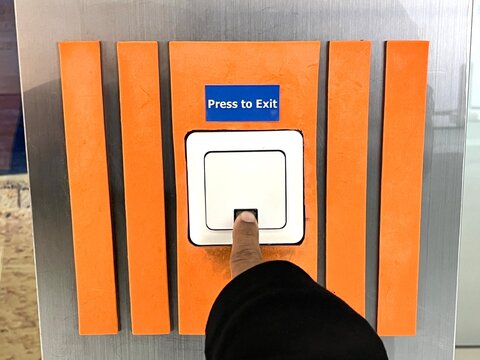 Initiating Access: A Human Finger Engages the "Press to Exit" Button to Activate an Automated Sliding Door, Highlighting the Interaction Between User and Modern Building Technology
