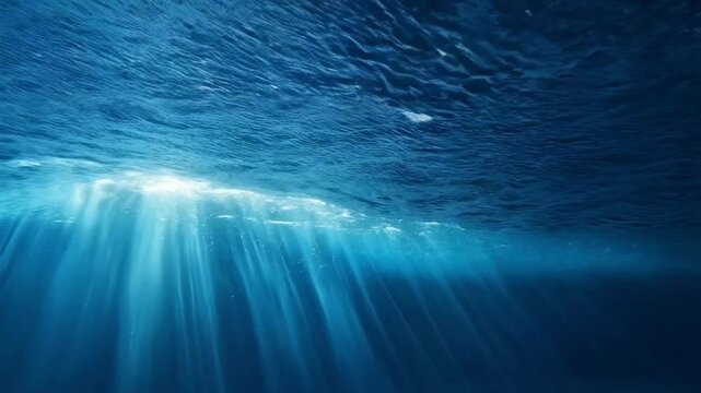 Underwater scene with sun rays penetrating the surface of the deep blue ocean