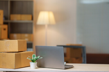 Startup small business sme owner entrepreneur using a laptop with boxes ready to be shipped on a...