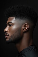 Profile of a young man showcasing a stylish haircut with a modern fade and textured top against a dark background