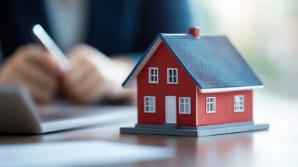 House model on desk, person works