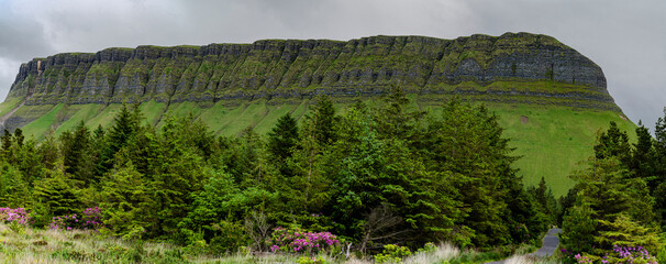 Ben Bulbin panorama part of the Dartry range with a cloudy sky and a forest at it's base and a road as a leading line