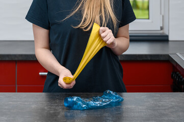 Kobieta rozrywa żółte worki na śmieci I wyrzuca zużytą butelkę z plastiku po wodzie, segreguje smieci © Paweł Kacperek