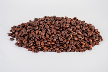 Pile roasted coffee beans isolated on a white background.
