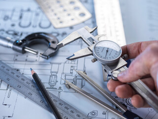 Close-up of engineering tools and calipers on a technical drawing for precision measurement