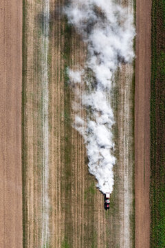 Aerial view of a tractor working in a cultivated lime field with a white cloud of dust
