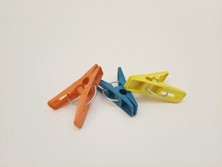 Clothes pins, three multi color plastic laundry clips or clothes pegs for house on the white...