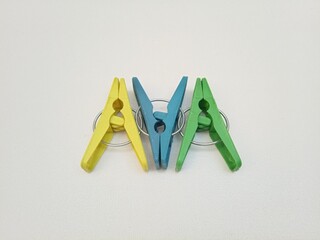 Clothes pins, three multi color plastic laundry clips or clothes pegs on the white background