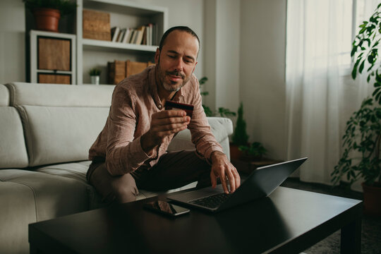 Man holding credit card near laptop at home