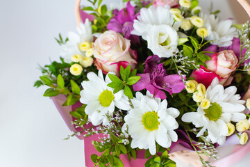 A beautiful bouquet of fresh flowers in pastel colors, including roses, daisies, and alstroemerias, arranged in a basket