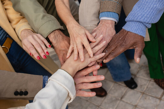 A diverse group of seniors joining hands outdoors symbolizing unity and camaraderie