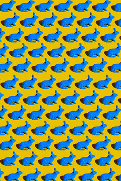 Blue plastic rabbits forming a pattern on a yellow background