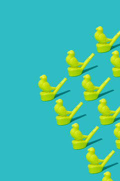 Yellow plastic bird-shaped whistles arranged in a triangular formation on a blue background