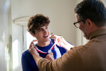 Father awarding son with a medal at home