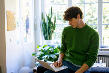 Young man working on a laptop at home in a relaxed setting