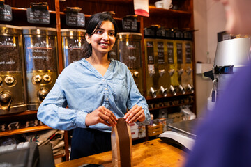 Young woman working in a local coffee roastery serving a customer