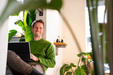 Businessman working remotely in a caf� with a laptop surrounded by plants