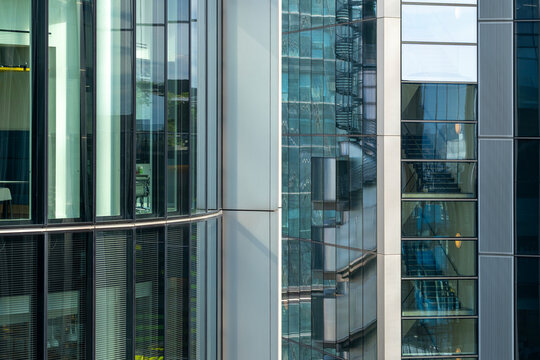 Glass buildings with visible technical elements and blue reflections in London's modern district, highlighting transparency, detail, and structural precision.