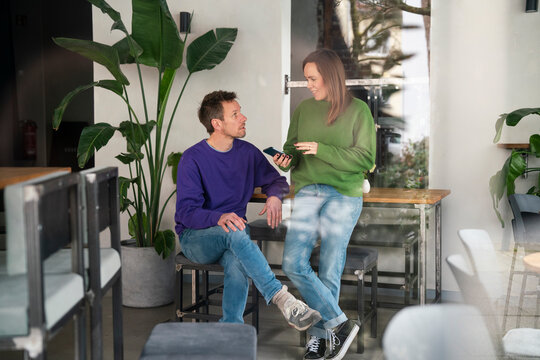 Two people having a business conversation in a caf� with a smartphone - Powered by Adobe