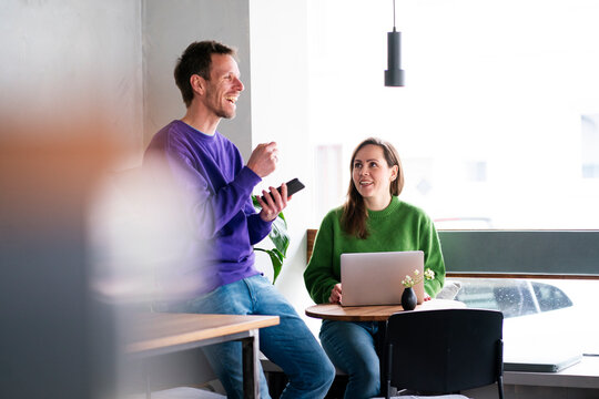 Two people working and communicating in a caf� with a laptop and smartphone - Powered by Adobe