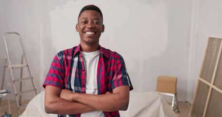 Standing in a renovated apartment, a man crosses his arms over his chest, smiling with pride....