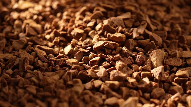 Closeup of a heap of freeze-dried coffee, rotating under bright sunlight, with blurred background