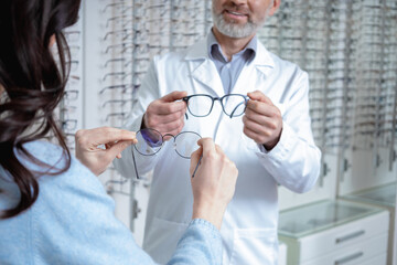 Female customer choosing new glasses in optic shop