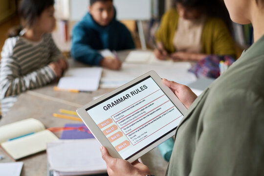 Teacher conducting language class using digital tablet with students in classroom