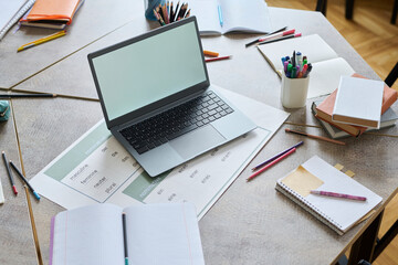 Laptop on desk with educational materials and stationery in a study setting