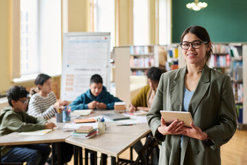 Young female teacher with tablet in a classroom setting with students